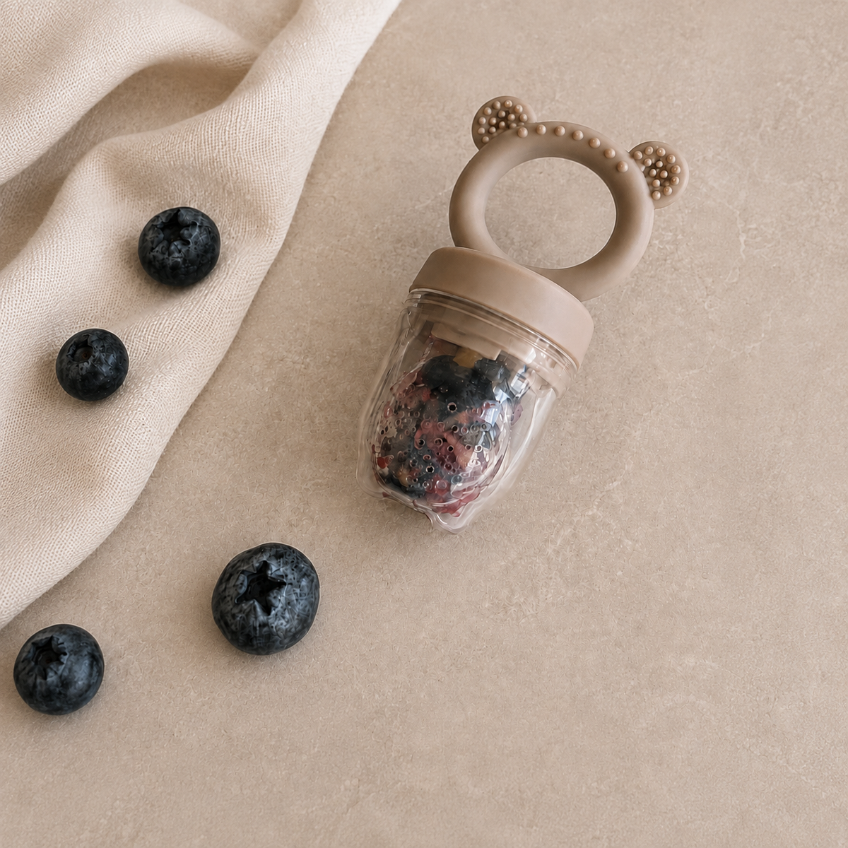 Grignoteuse bébé en silicone taupe avec poignée ours, remplie de myrtilles